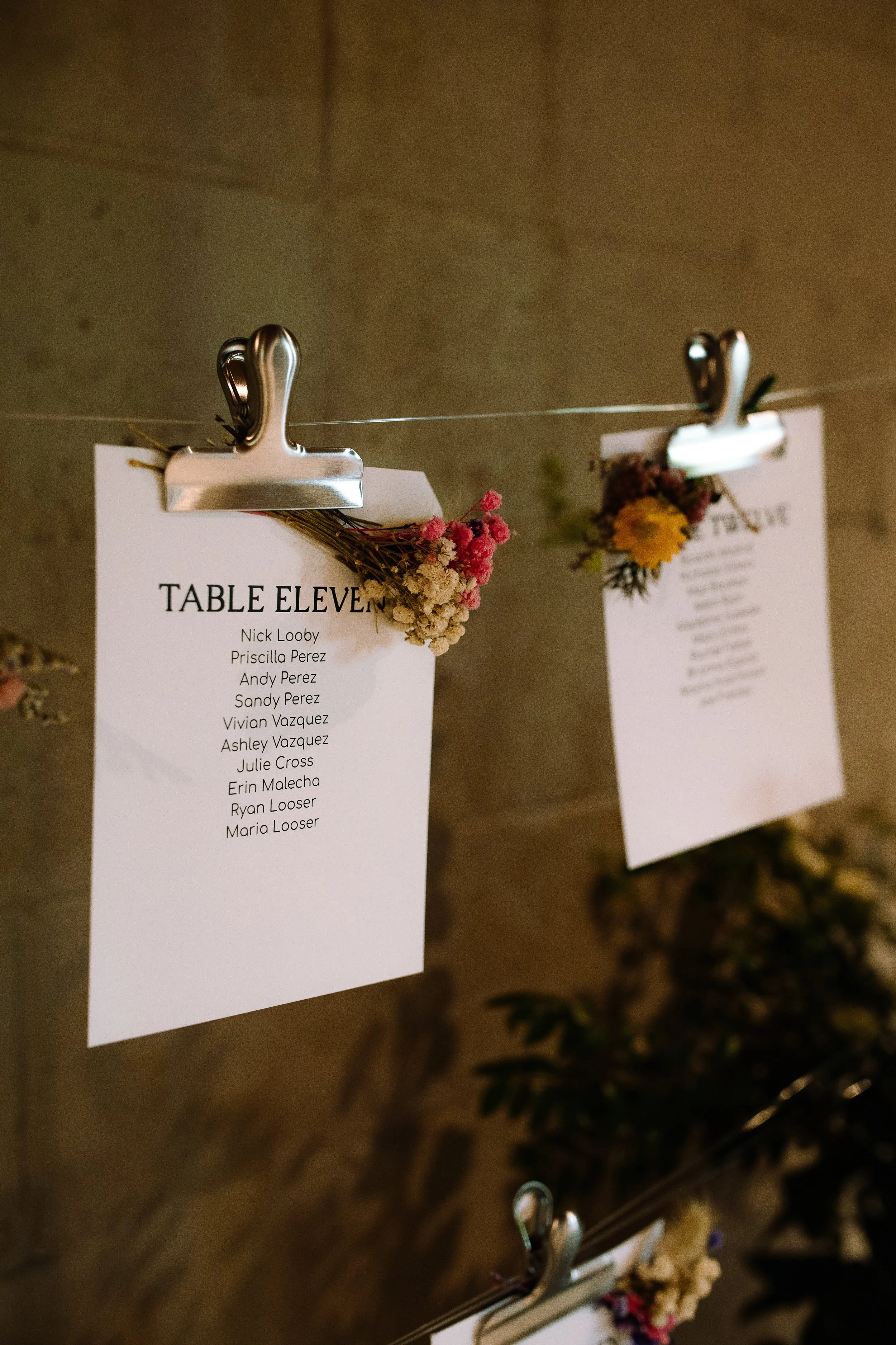 Close-up of wedding table assignment cards clipped to a display inside the historic barn at Jorgensen Farms.