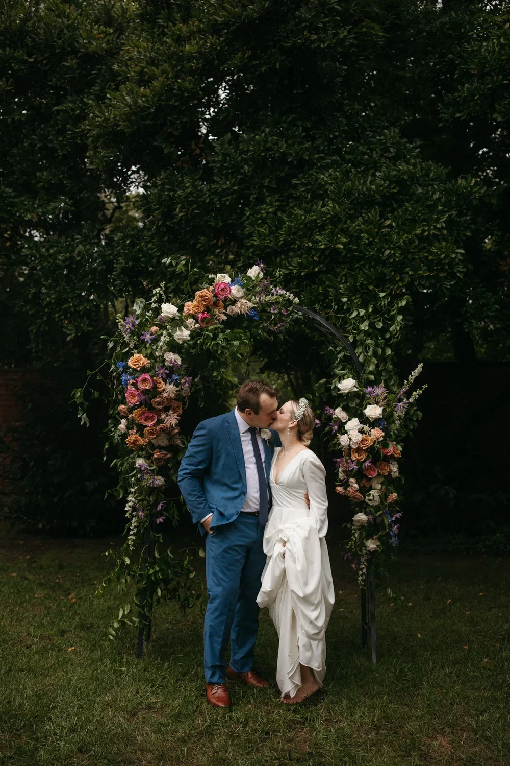 Couple kissing beneath a floral ceremony arch at a Peterloon Estate wedding in Cincinnati, Ohio