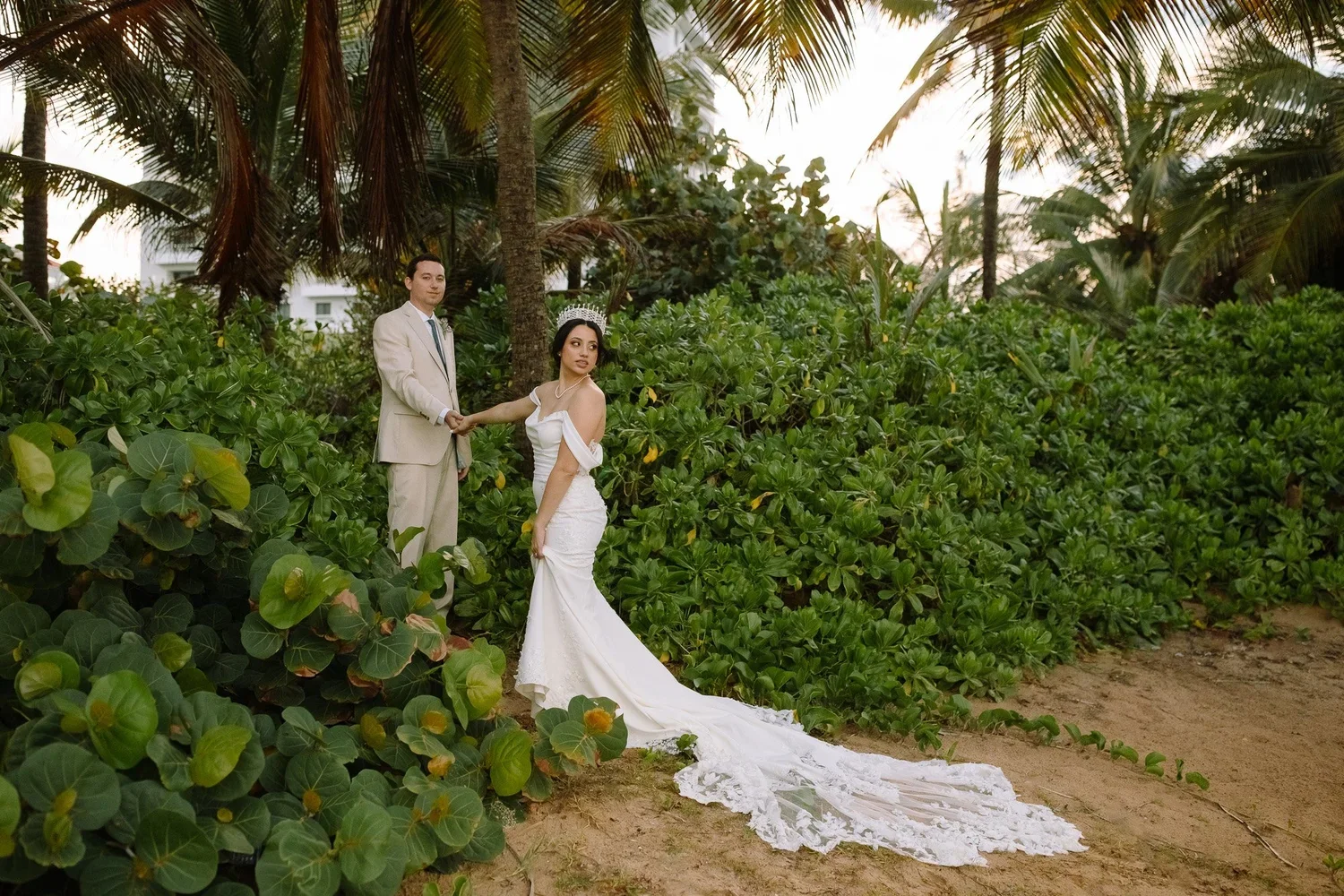 Bride and groom walking hand in hand through lush tropical greenery in Puerto Rico