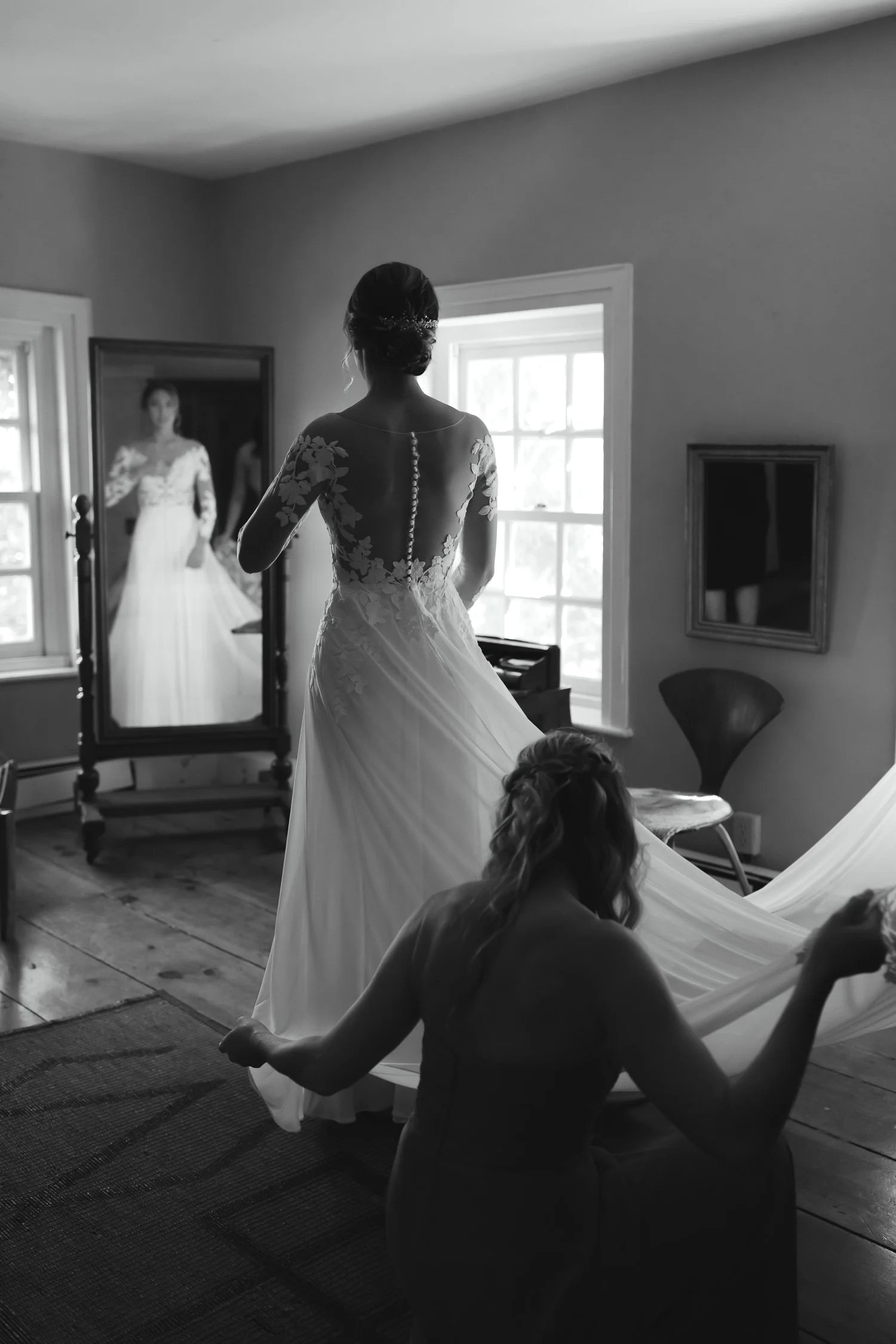 Bride getting into her wedding dress with bridesmaids helping during a Windrift Hall wedding in the Hudson Valley