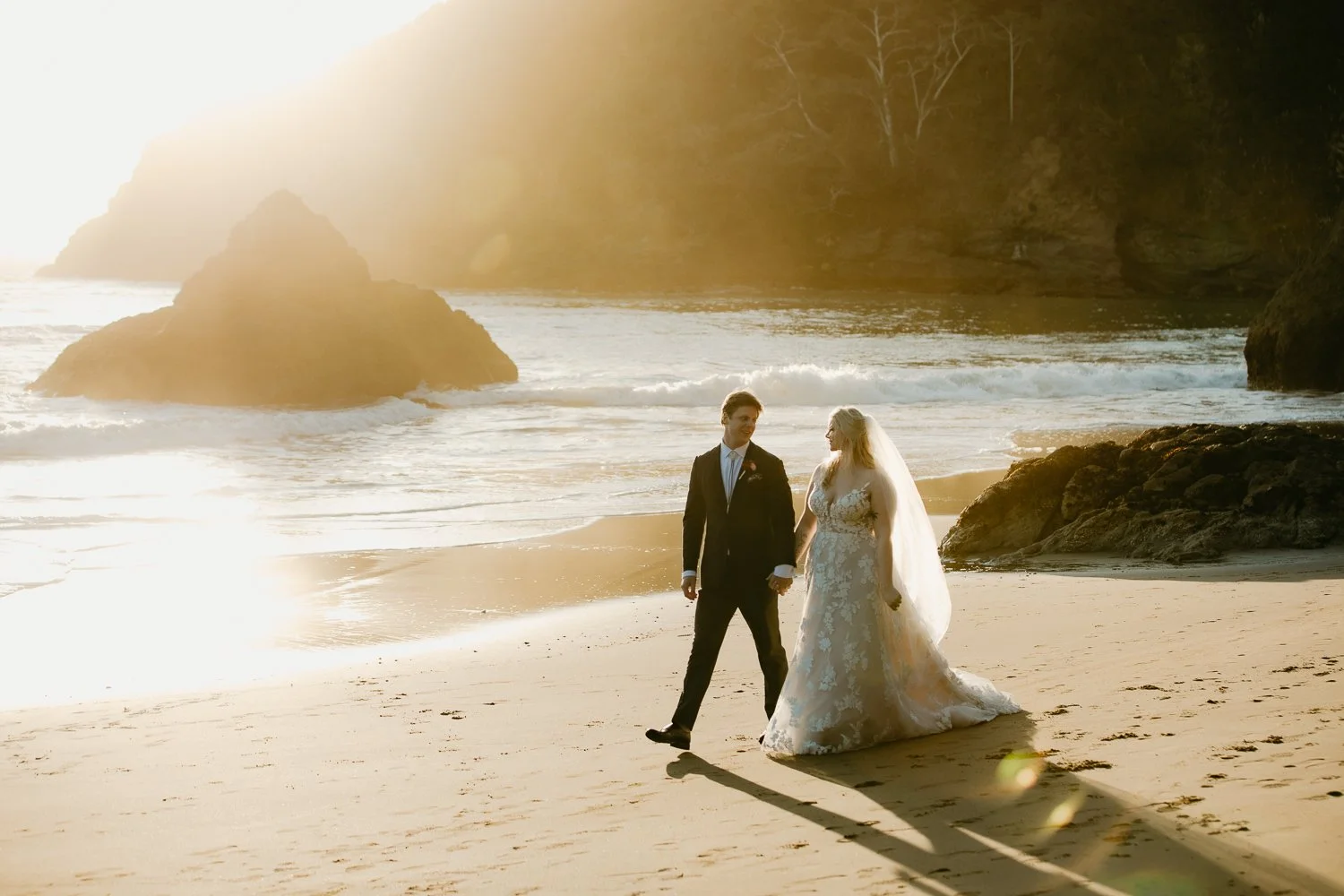 Couple walking along a Northern California beach at sunset after their elopement