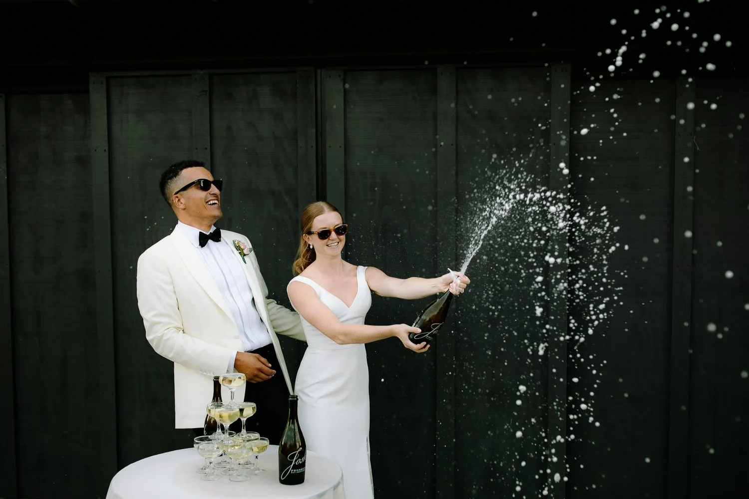 Bride and groom popping champagne and celebrating during their wedding reception.