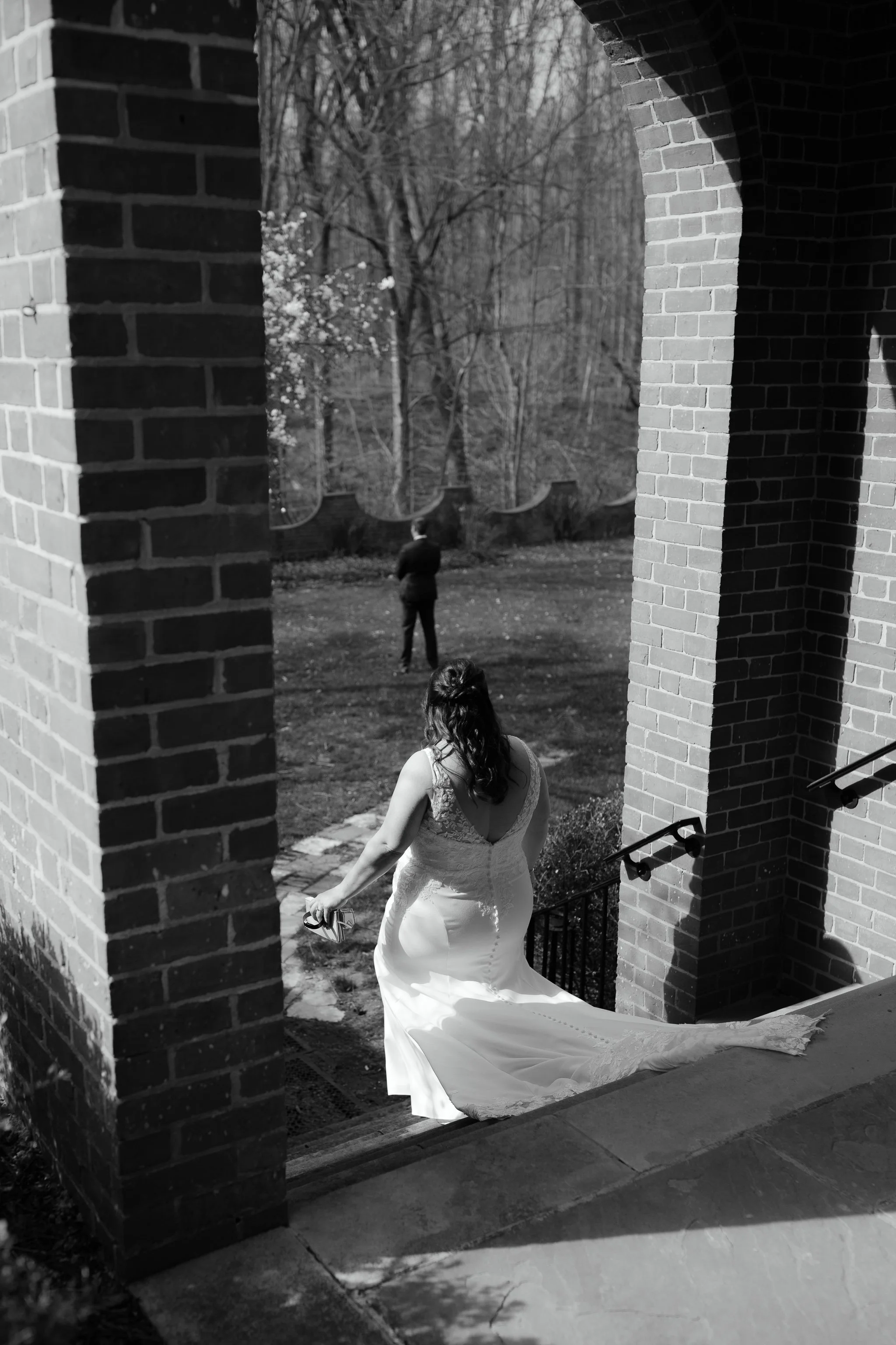 Bride walking down steps beneath brick archway at Peterloon Estate