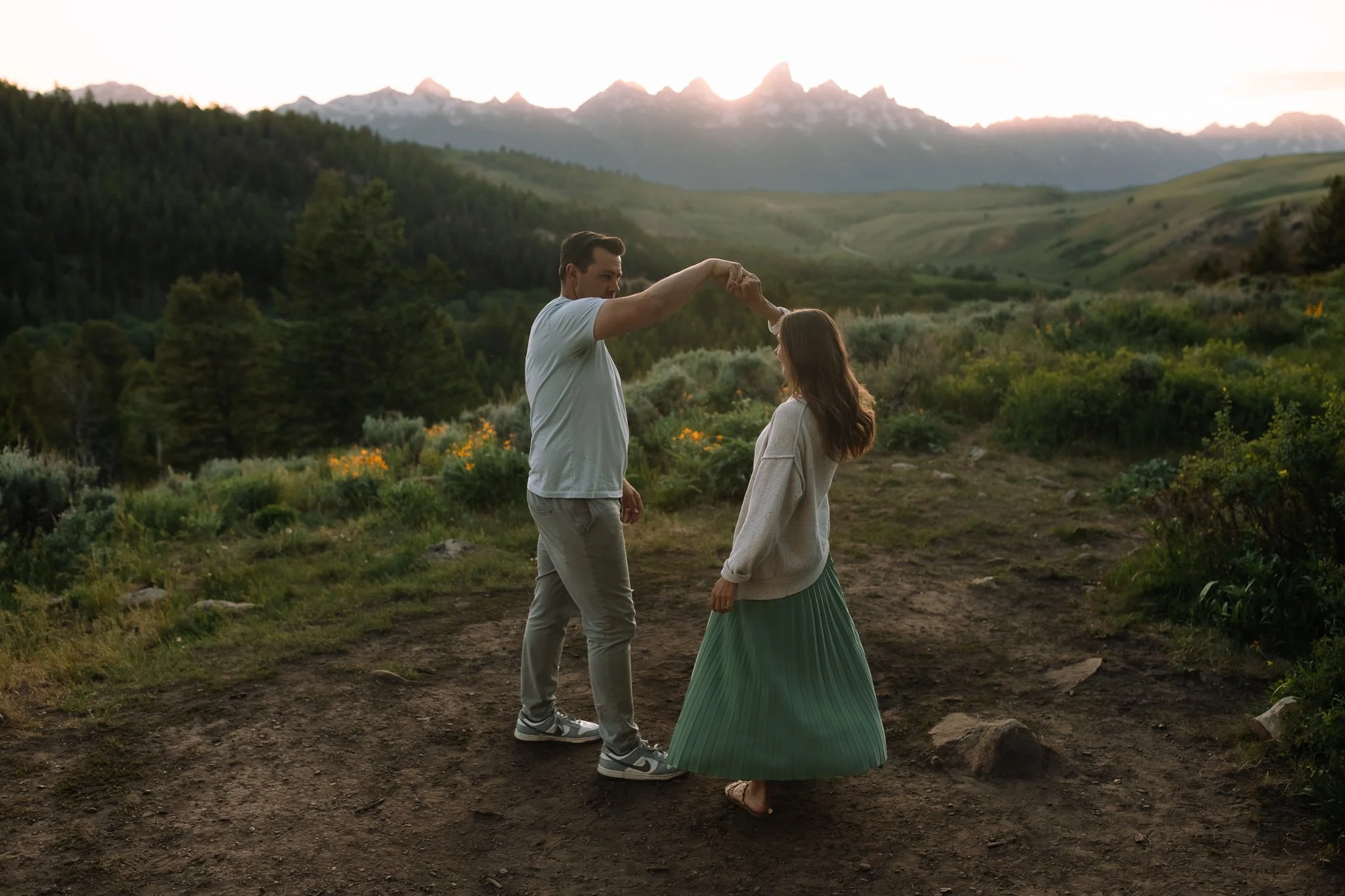 Couple hiking together during sunset in Grand Teton National Park with mountain views behind them.