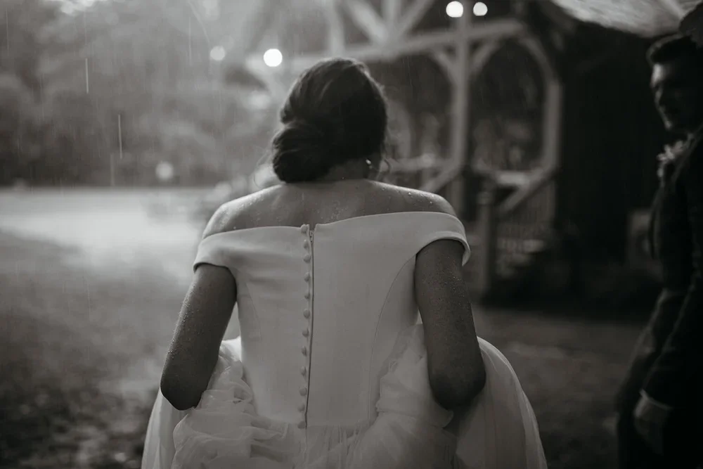Bride walking into reception space on a rainy evening wedding with soft backlight and dramatic atmosphere.