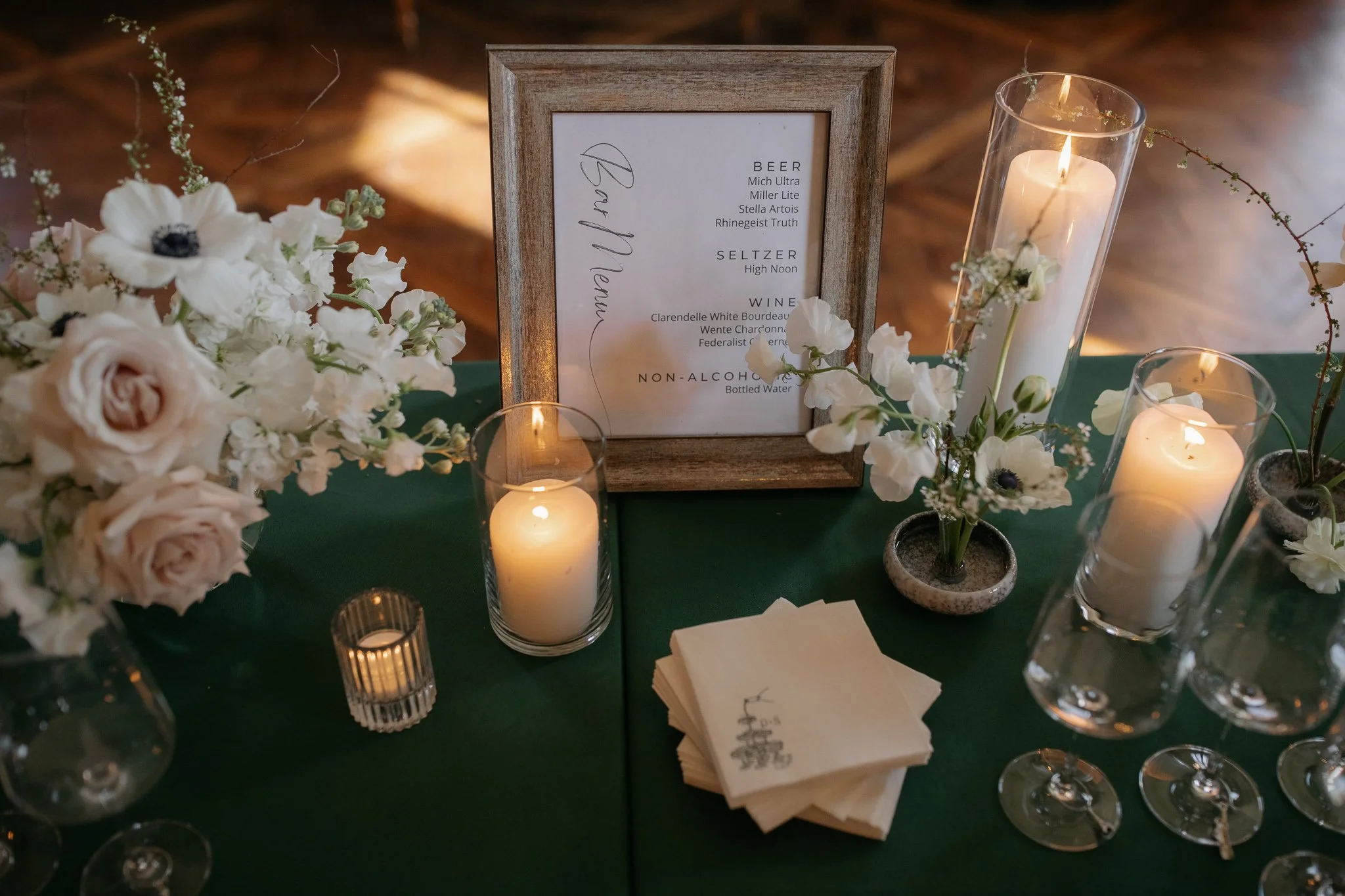 Cocktail hour table with candles, florals, and signage in grand room
