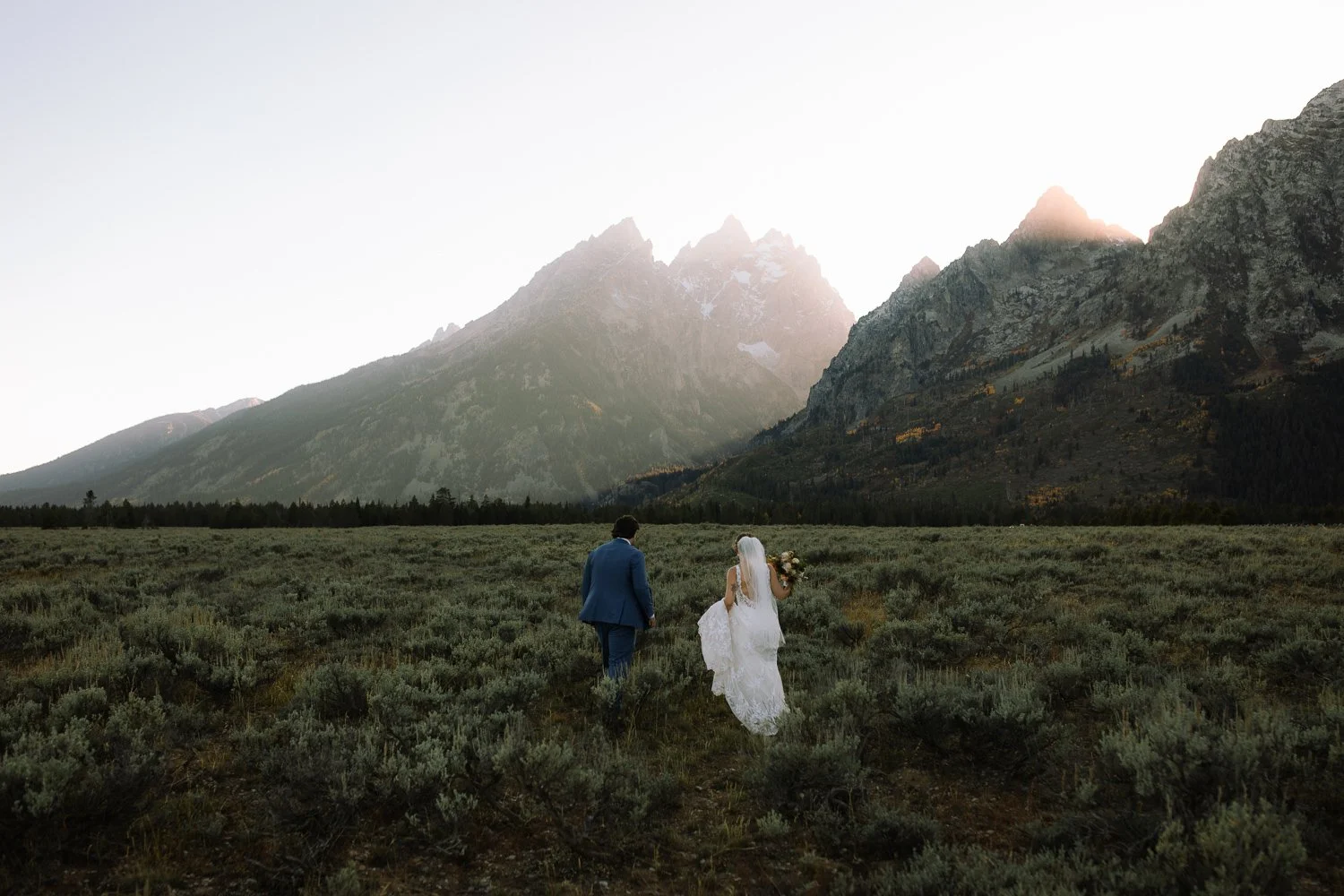 Couple walking through sagebrush during sunset portraits in Grand Teton National Park.