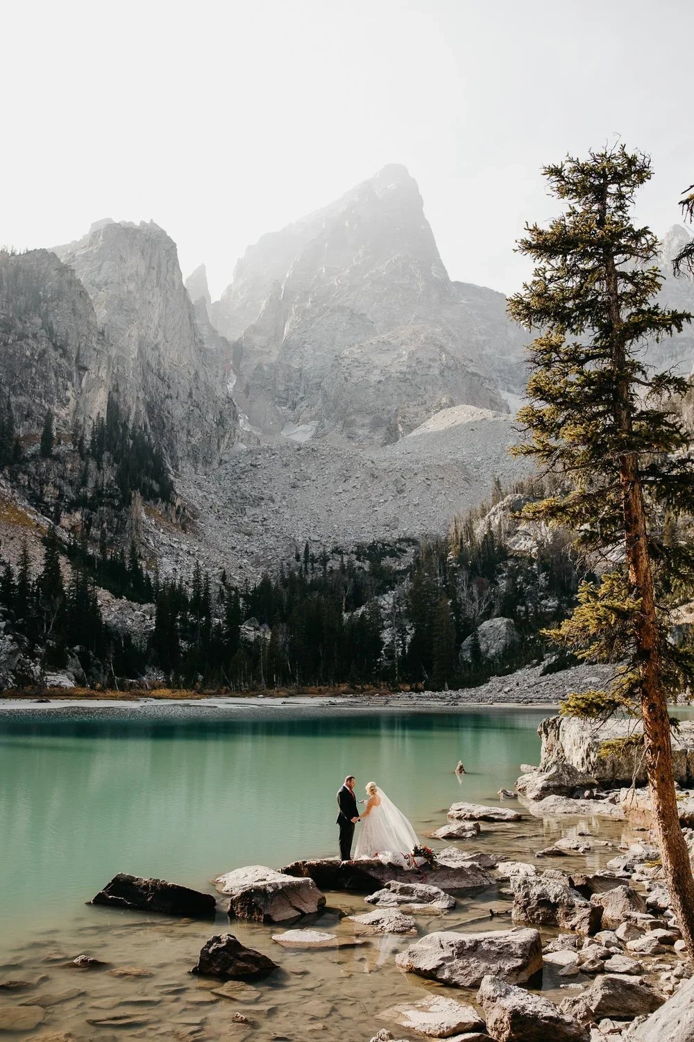 Couple standing together during an elopement ceremony along the shoreline of Delta Lake in Grand Teton National Park.