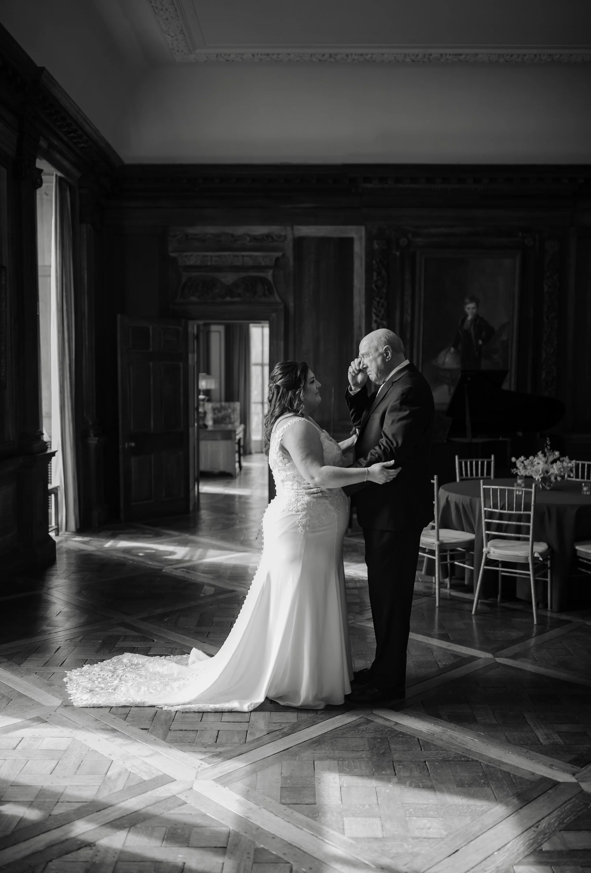 Black and white image of father and daughter first look in grand room at Peterloon Estate