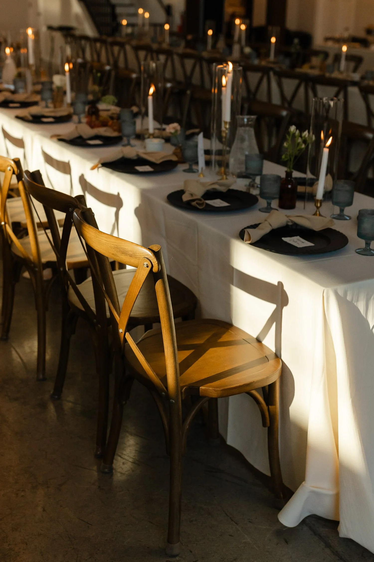 Candlelit wedding reception tables and wooden chairs inside Ivory Meadows in Dayton, Ohio