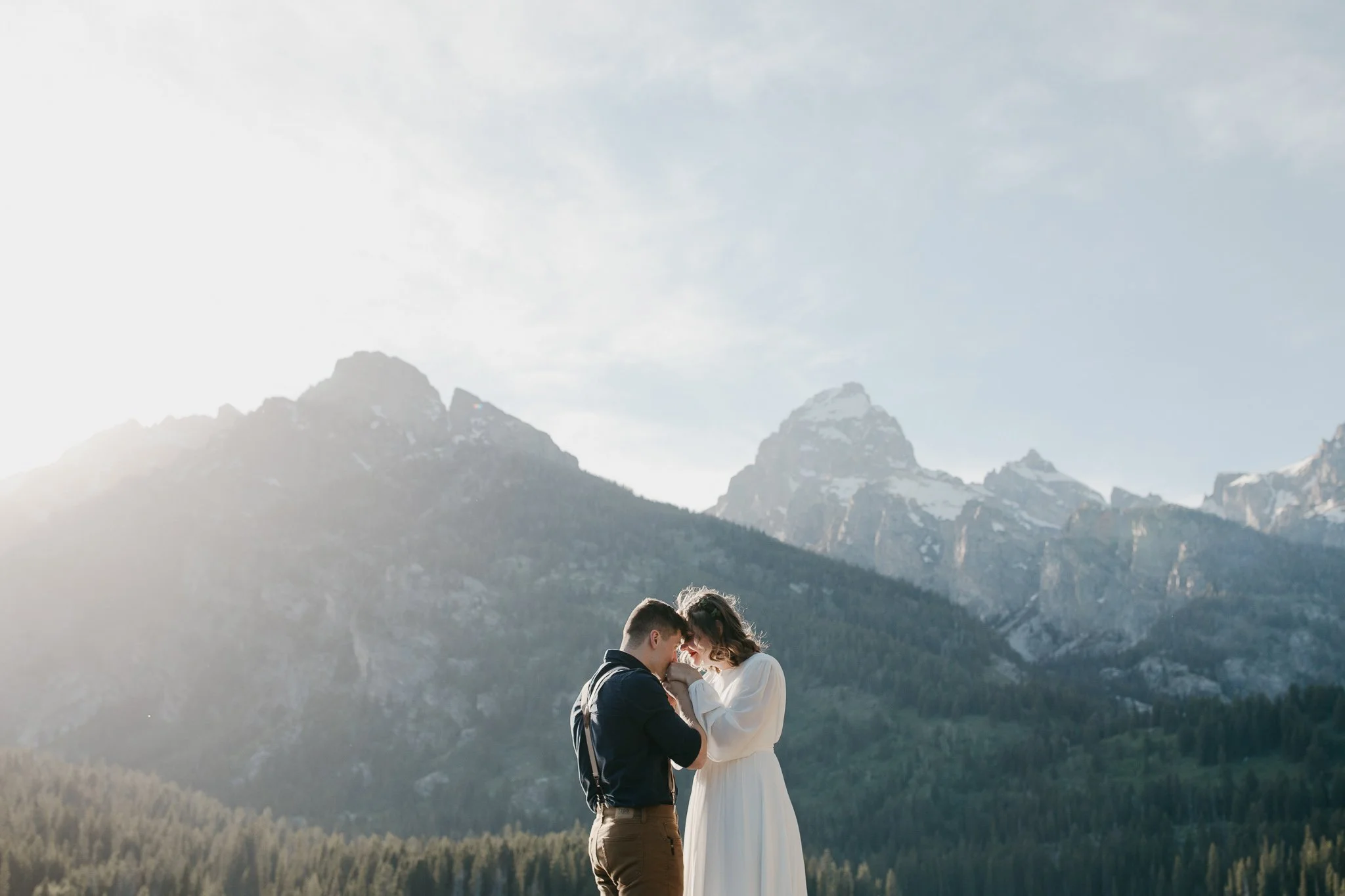 Couple sharing a quiet moment together at sunrise with soft light over the Tetons