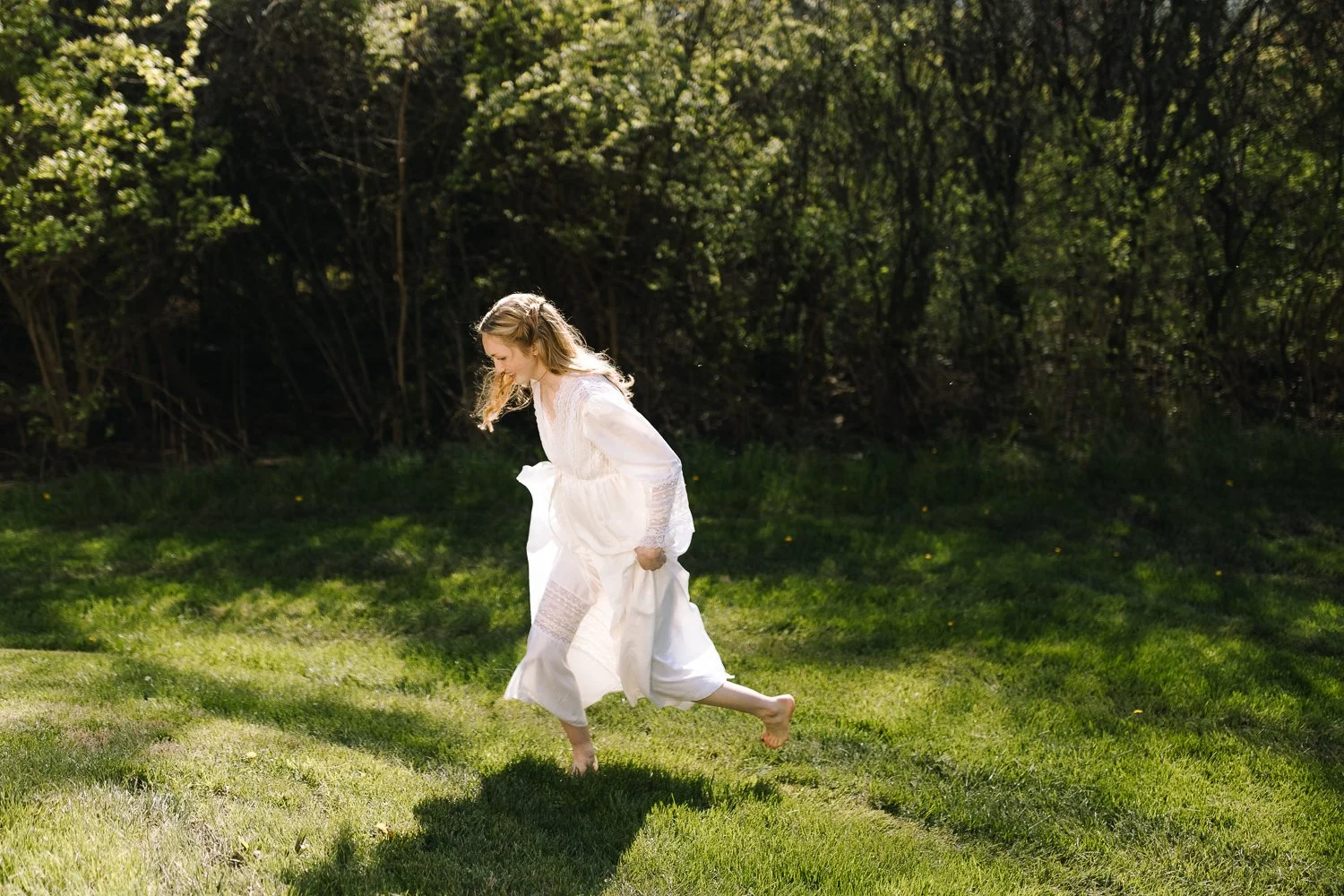 Bride running barefoot through grass during outdoor wedding captured in natural light