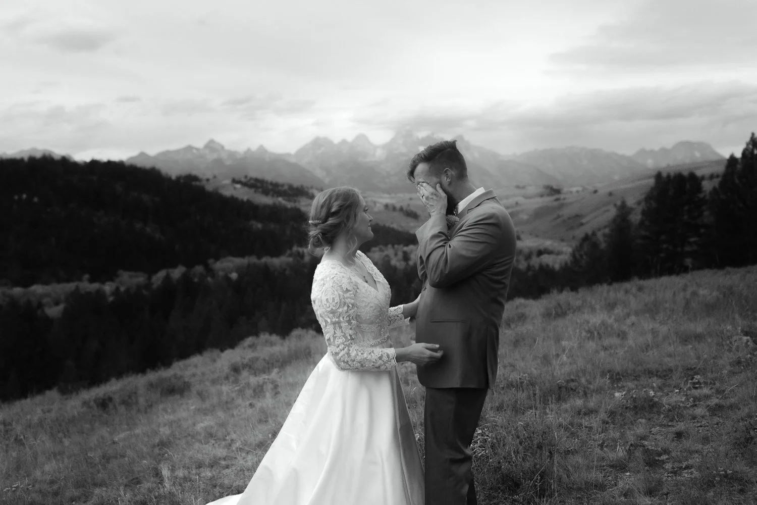 Groom wiping tears during mountain wedding portraits in Jackson Hole with Grand Teton range in the background