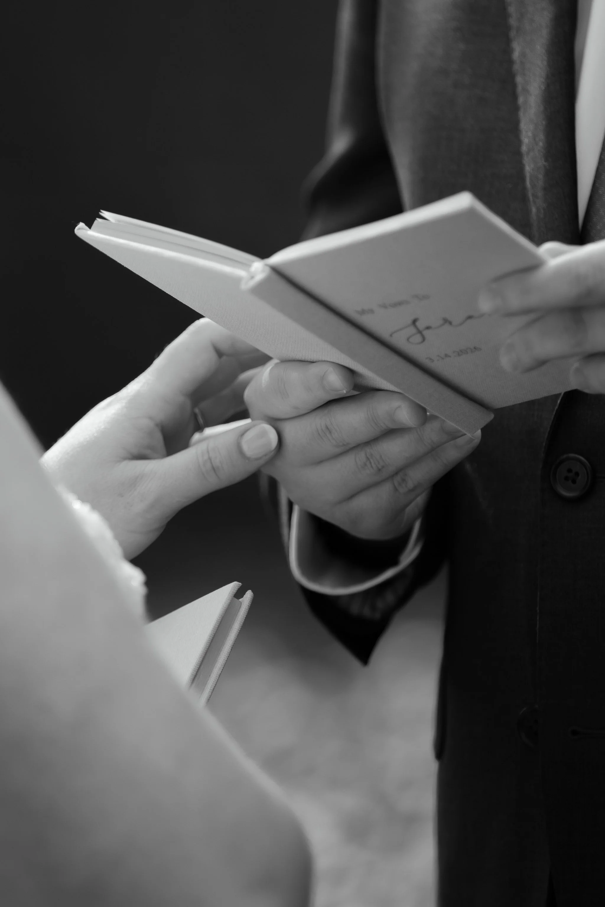 Close-up of hands holding vow book during wedding ceremony preparation