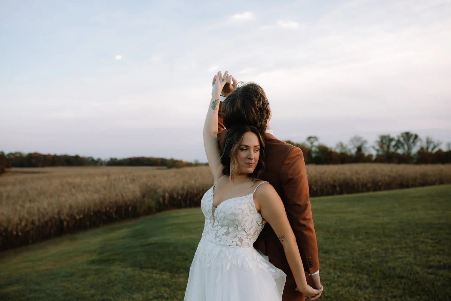 Candid moment of bride and groom standing back to back in a fall field during evening portraits at Ivory Meadows wedding venue in Dayton, Ohio.