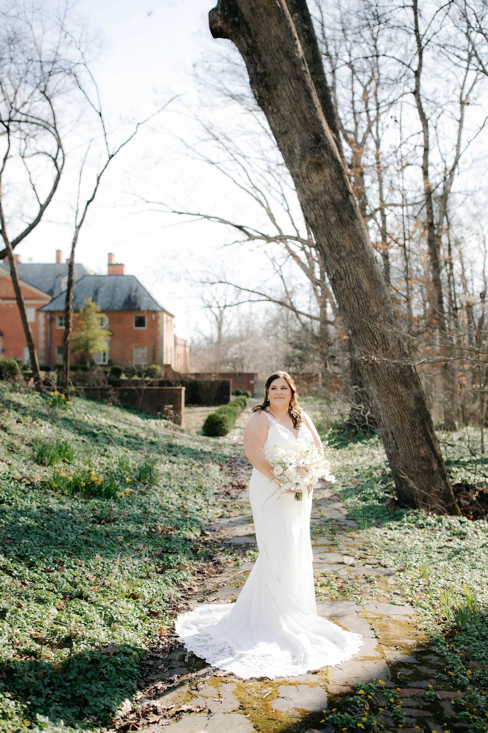 Bride standing in garden with trees and estate in background at Peterloon Estate
