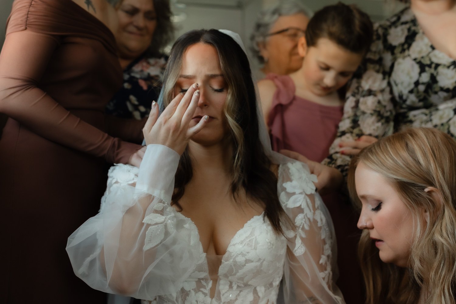 Bride wiping away tears during a prayer with loved ones before the ceremony at Ivory Meadows in Yellow Springs, Ohio.