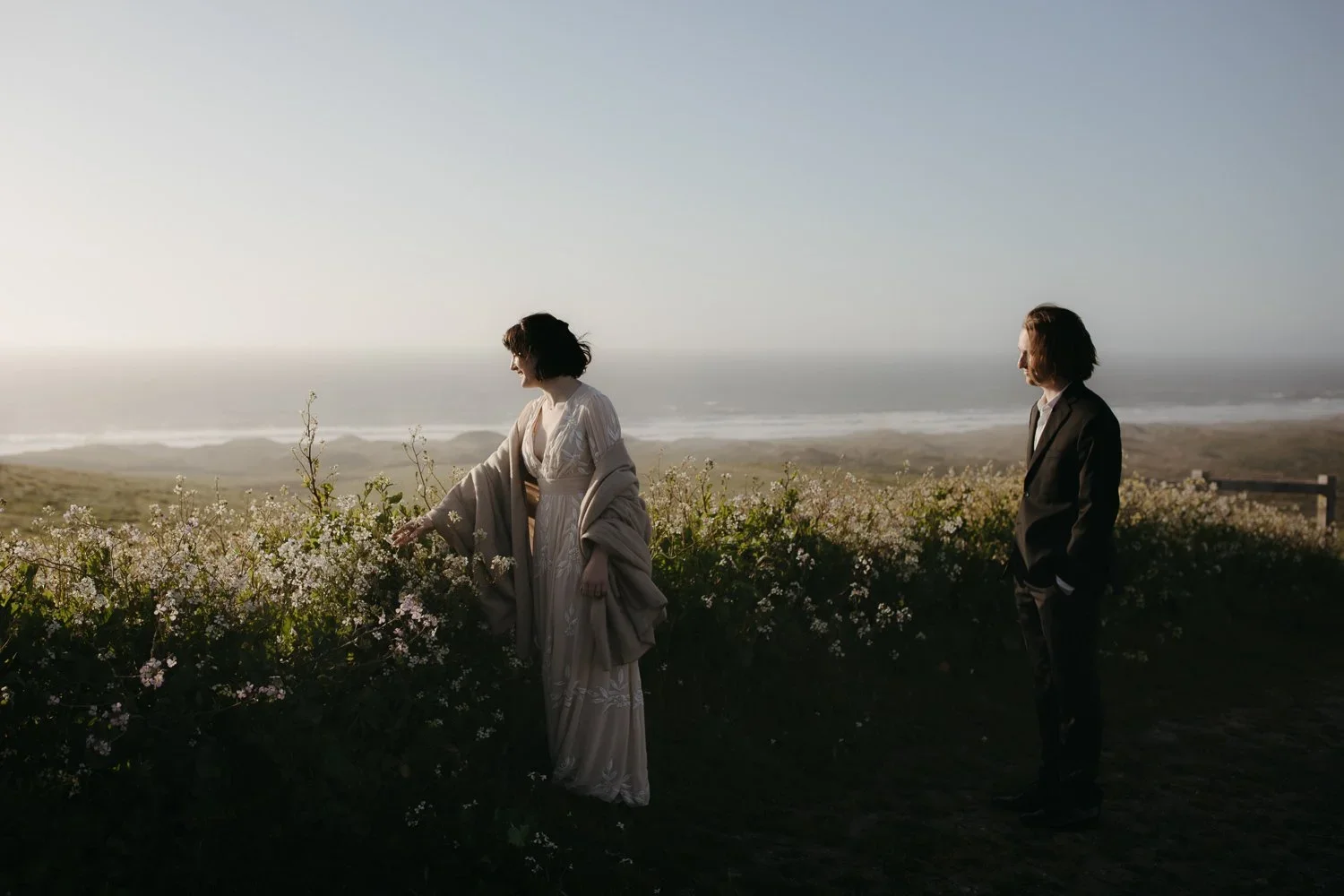 Couple standing among wildflowers with ocean views at Point Reyes National Seashore elopement