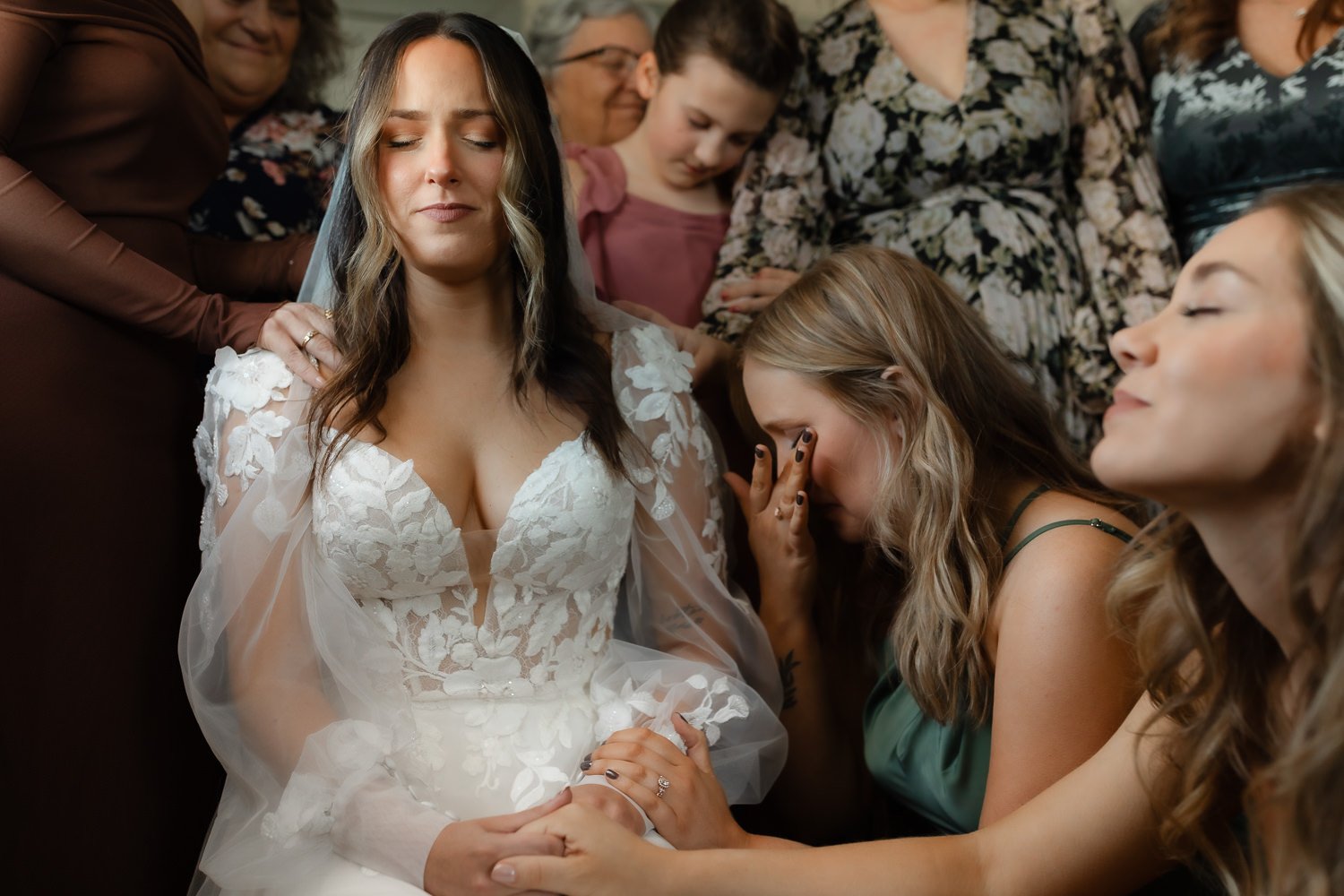 Bride surrounded by loved ones during a prayer moment in the getting ready suite at an Ivory Meadows wedding in Yellow Springs, Ohio.