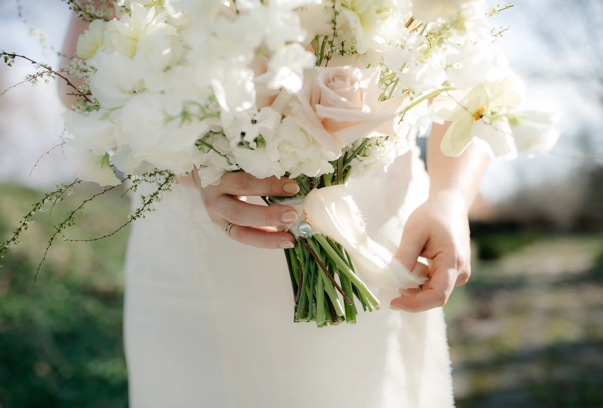 Bride holding bouquet with soft ribbon detail against wedding dress