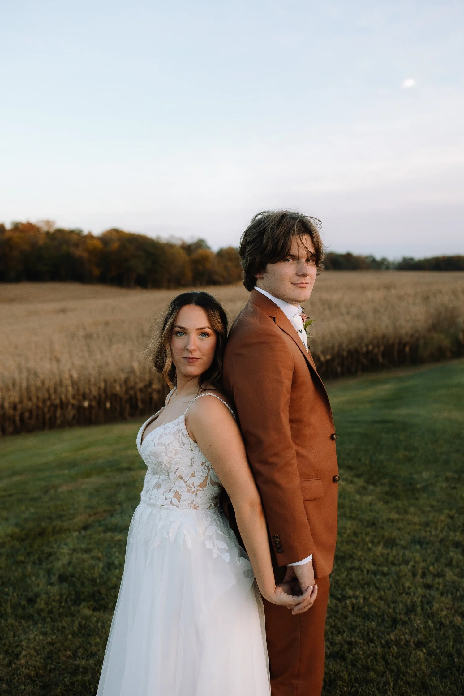 Bride and groom standing back to back in a fall field during evening portraits at Ivory Meadows wedding venue in Dayton, Ohio.