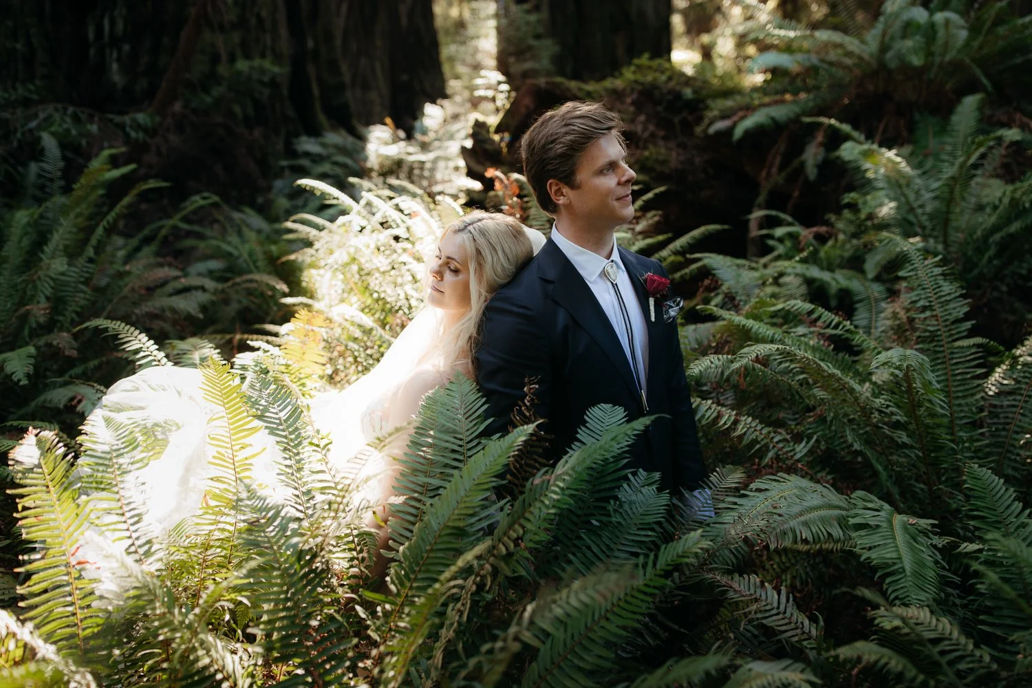 Couple standing among lush ferns during a Redwood National Park elopement, photographed by Eastlyn and Joshua