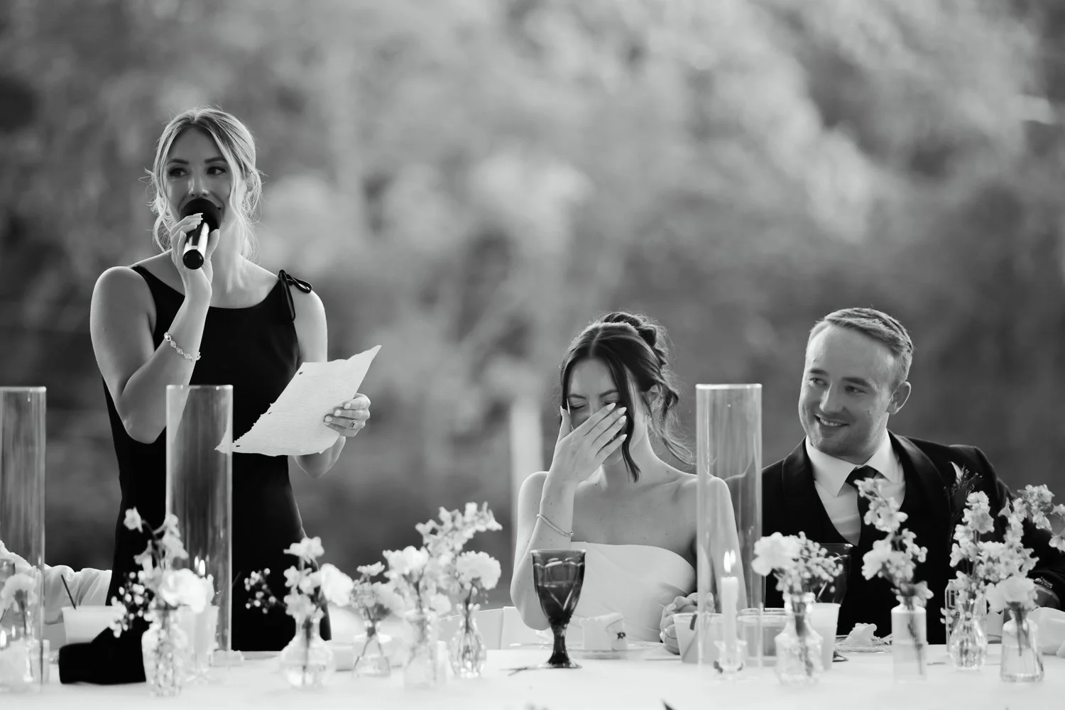 Bride reacting emotionally while maid of honor gives a speech at the wedding reception