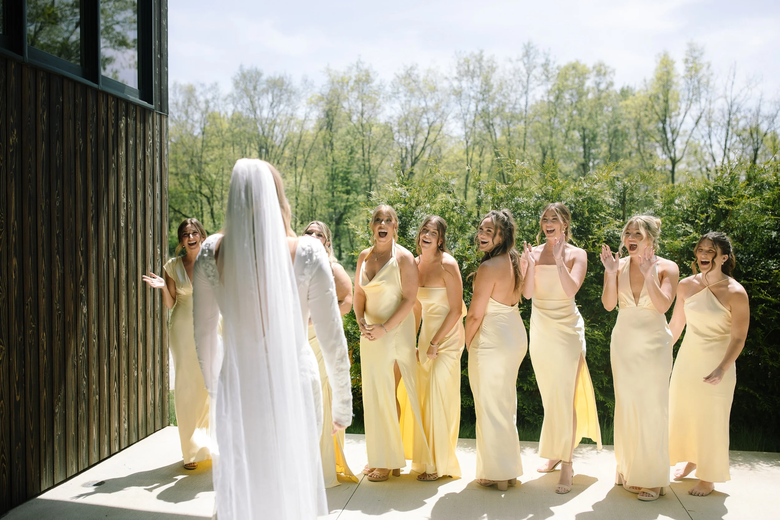 Bridesmaids in pale yellow dresses waiting outside for the bride during a spring wedding at Jorgensen Farm The Gardens.