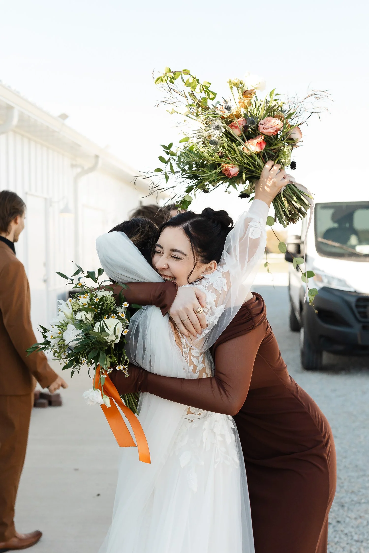 Bridesmaid hugging the bride in a joyful group hug following the recessional at Ivory Meadows in Dayton, Ohio.