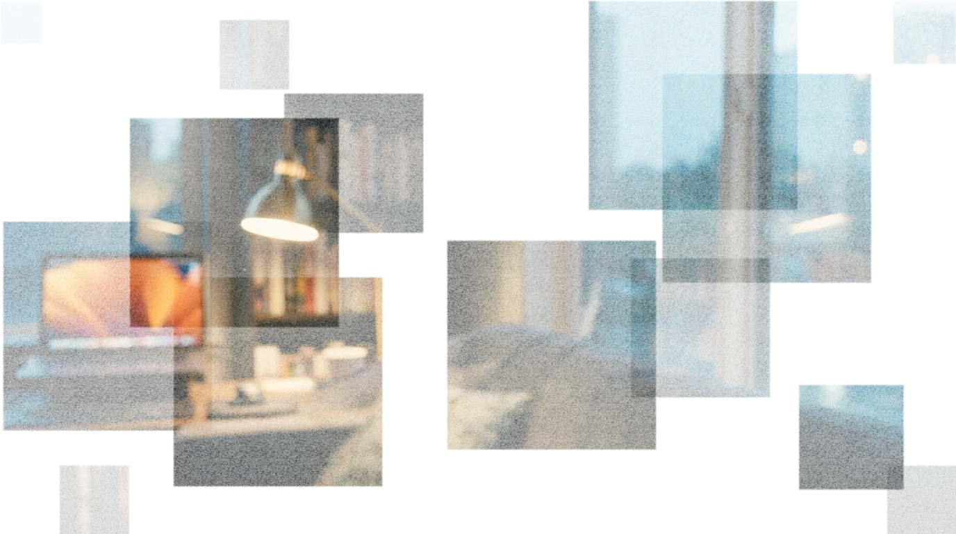 Cozy living room with large windows, a gray couch, bookshelf, laptop, and lamp.
