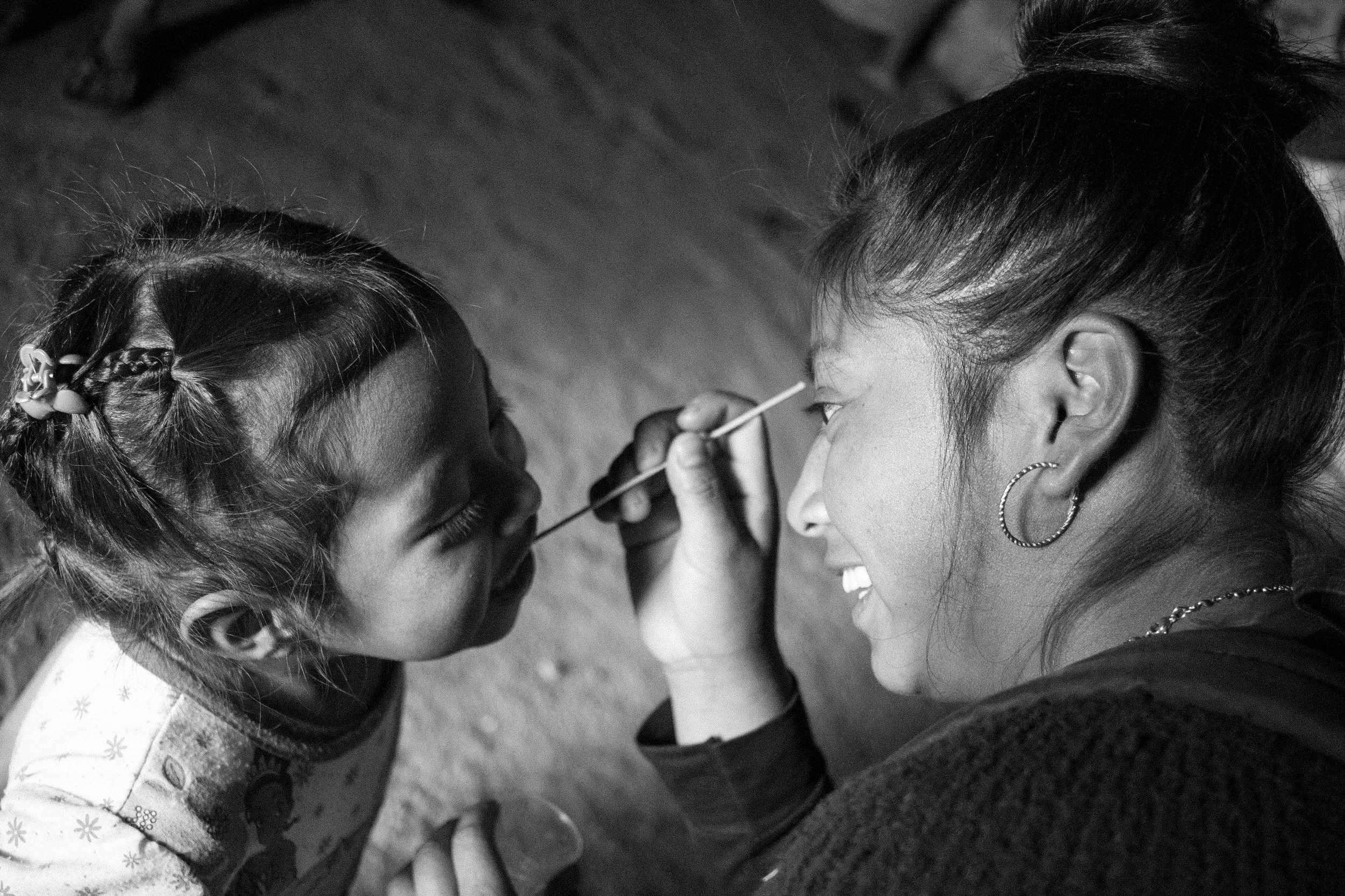 Yeny applying a floured treatment to a small girl in her village.