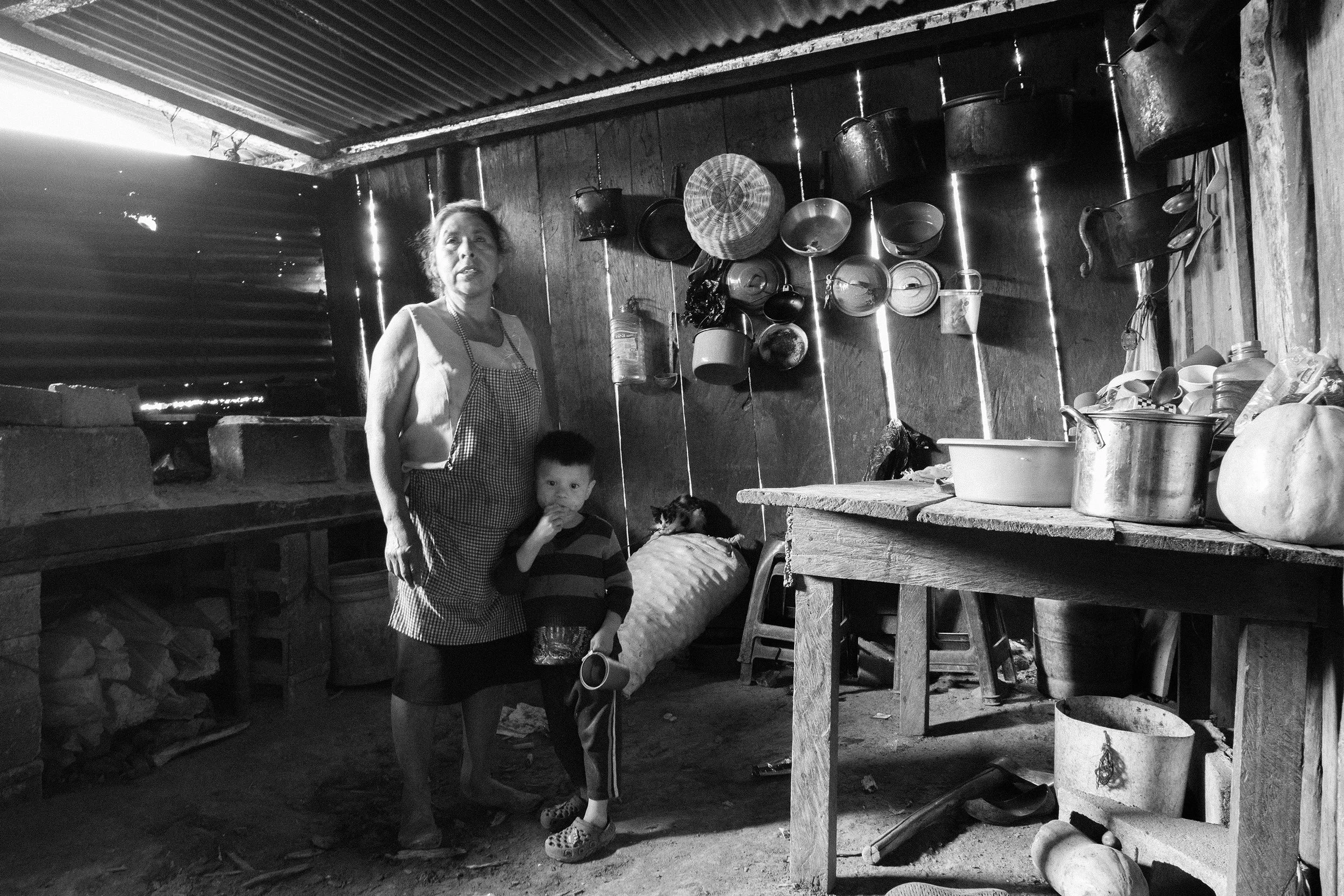 A Mayan mother and child stand in their rustic kitchen in the highland village of El Bejucal.