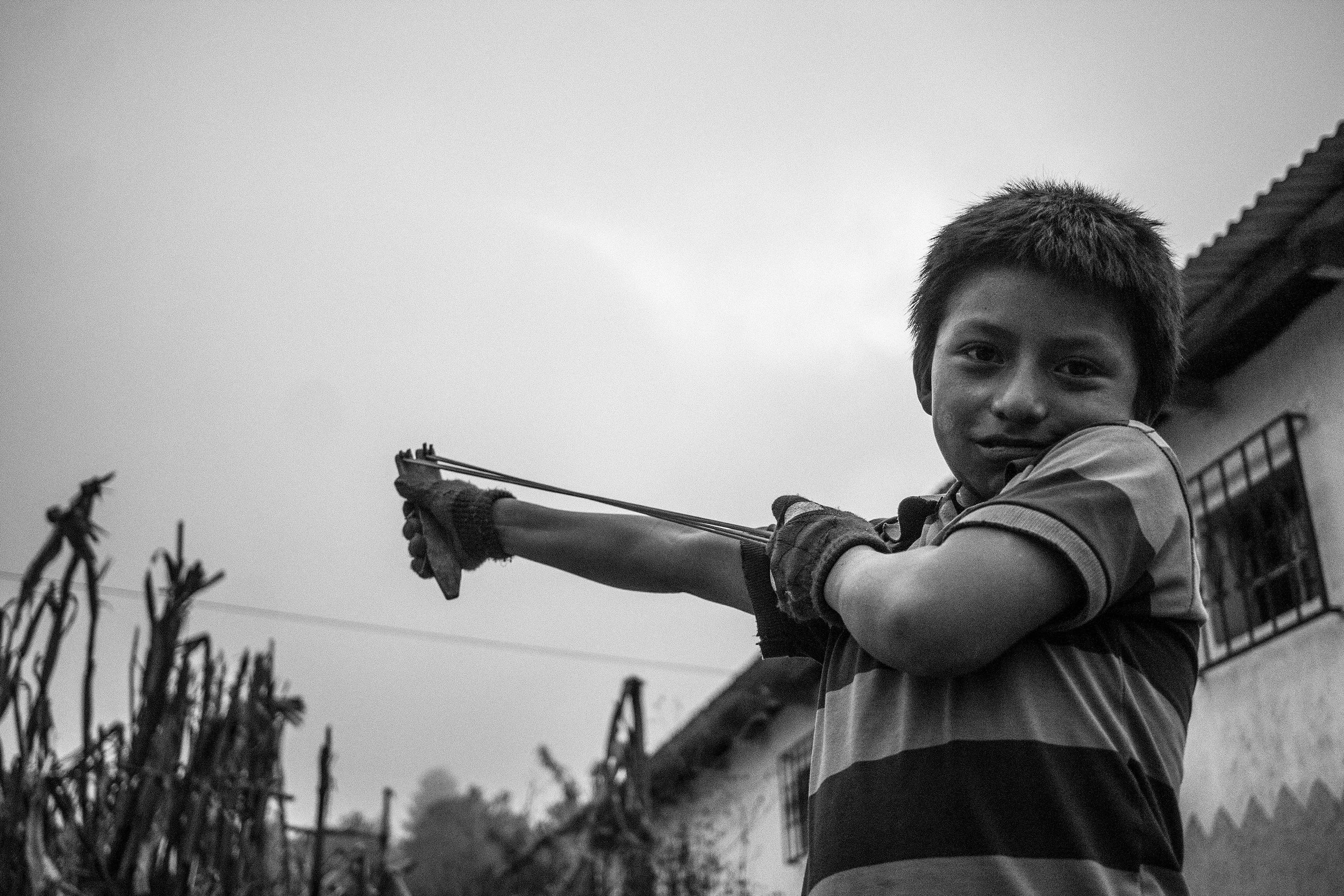 A Mayan boy plays with his slingshot in the highland village of Chuacorral. Sling shots are a common toy amongst Mayan children and are also used as a tool to knock avocados from tree tops.