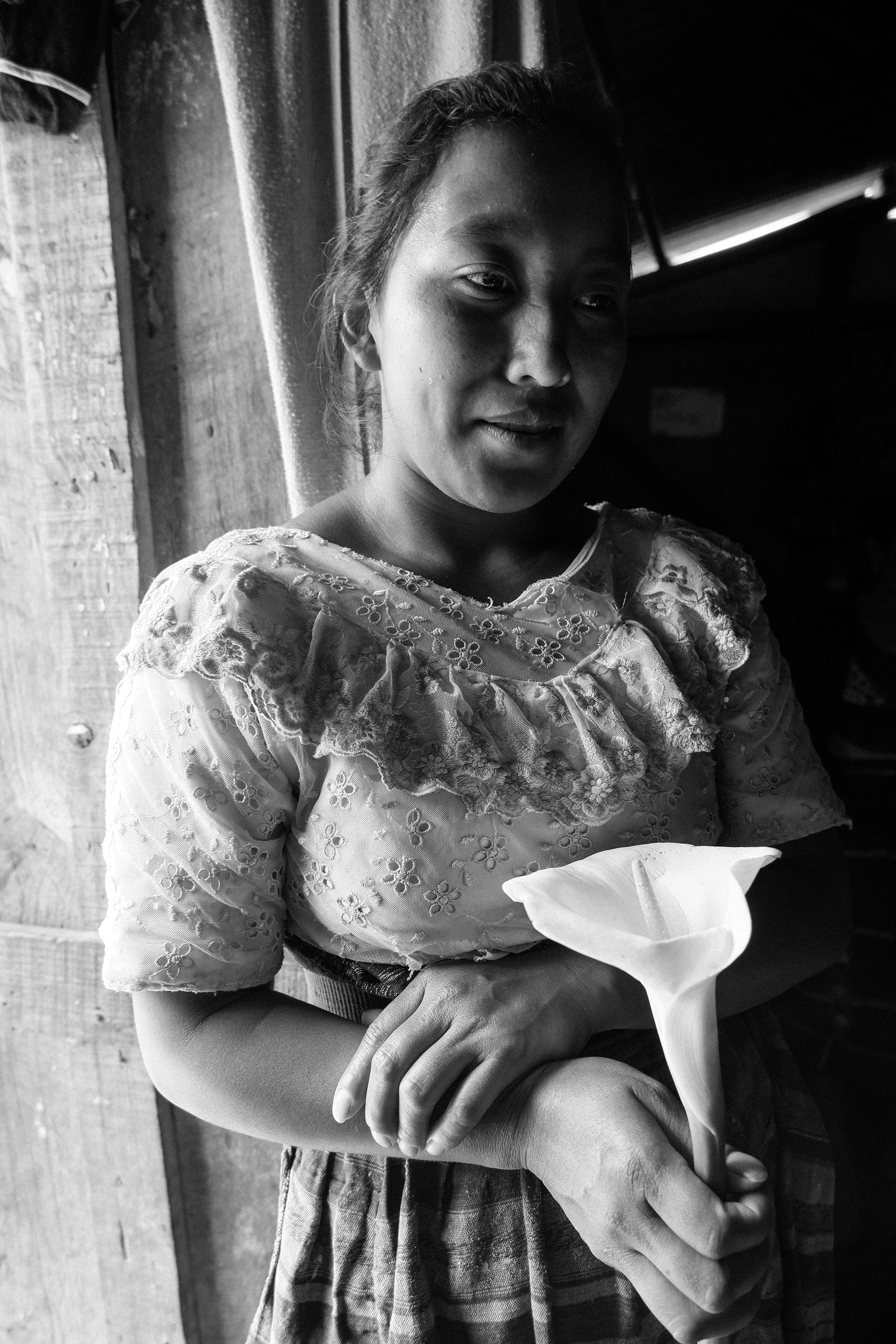 A Mayan girl holds a freshly cut tulip in her home in a small mountain top village outside the community of San Andrés Itzapa.