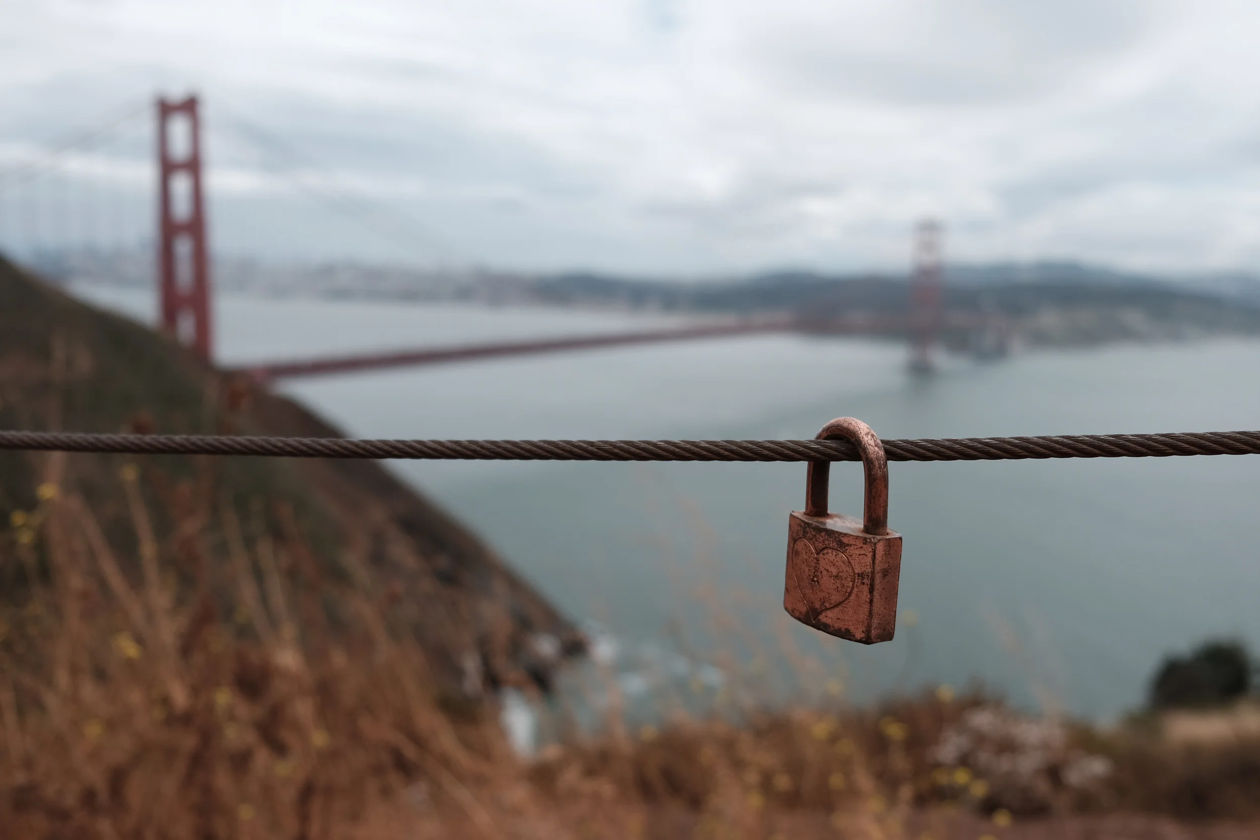 Lock attached to fence cable, located at a viewpoint above the Golden Gate Bridge, Marin Headlands, June 2016