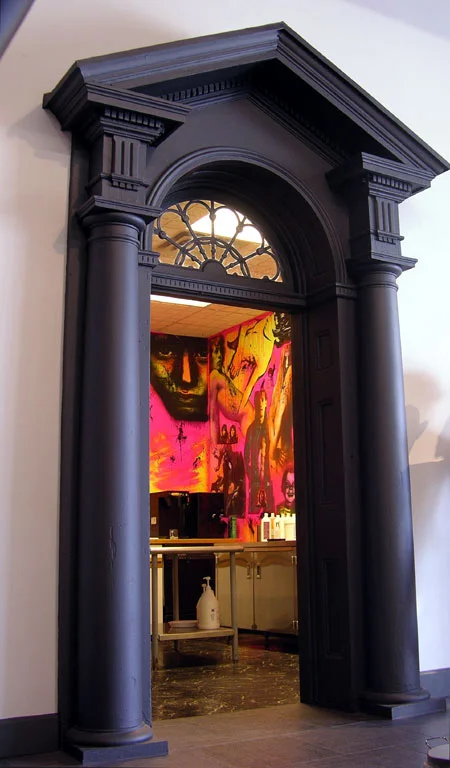 Color and texture is at play in the main entrance of the salon, as one entrance is surrounded by sheets of corrugated plastic, while the other frames the entrance to the back color room. Monochromatic grays are paired with bright hues of reds and pinks giving the area depth. Local artist, John Grider was commissioned , adding character and interest with graphic paintings that fills the wall across the doorways.