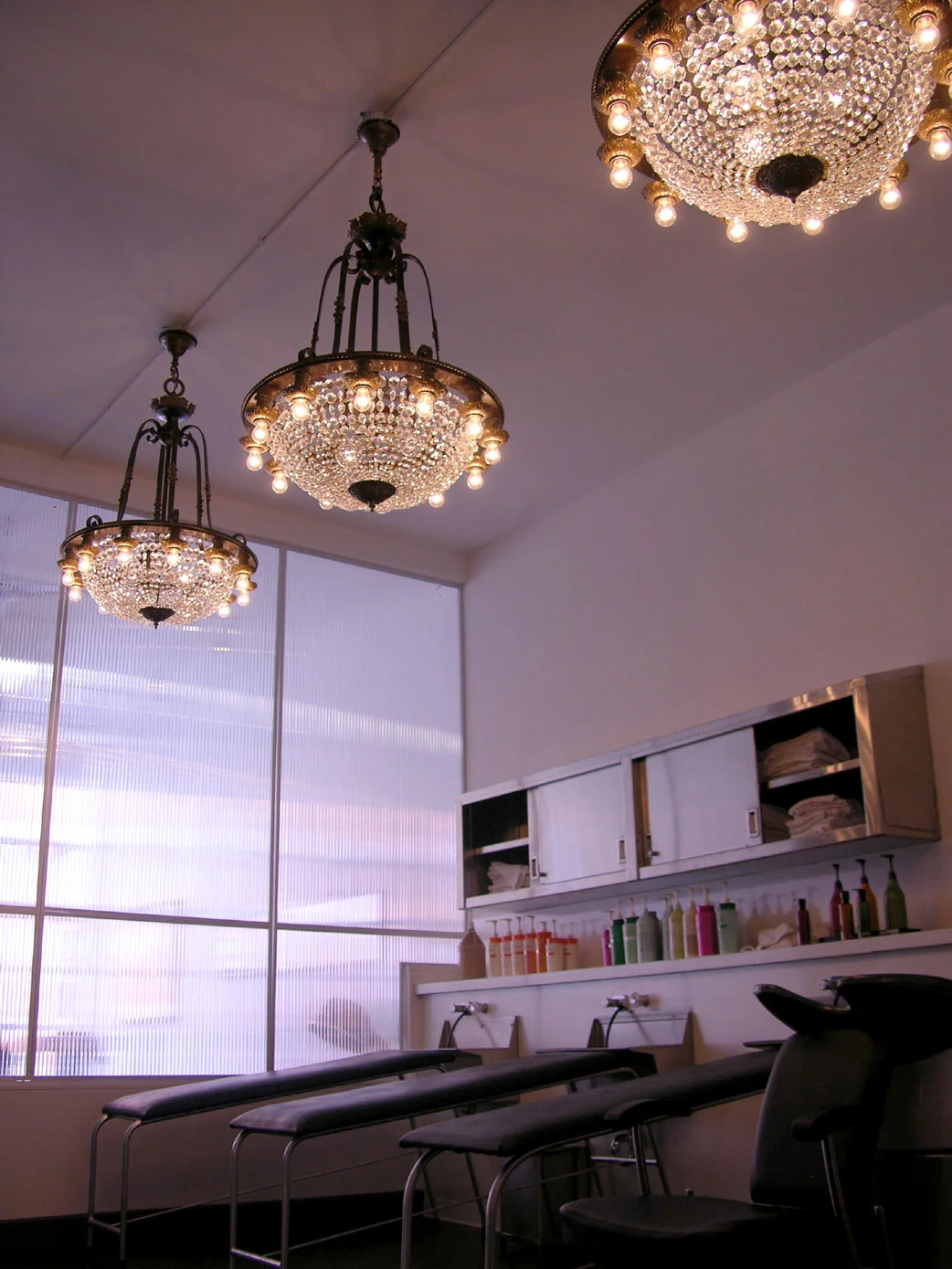Lighting also plays an important role in this space. A superb mix of antique crystal chandeliers are found throughout the salon. Over the shampoo area, the clientelle are able to lay back and relax while viewing a set of three matching chandeliers of iron, bronze and crystal salvaged from a federal building near Canon, Pennslyvania.