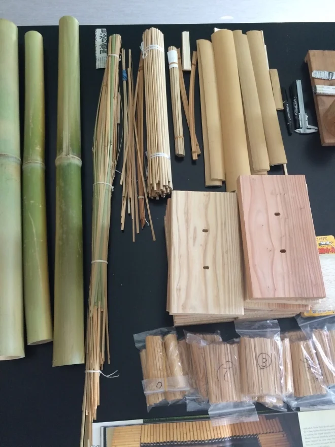 Workshop materials: whole Aodake, higo strips, blocks of hinoki for supporting reeds-in-progress, and packets of prepared reeds.