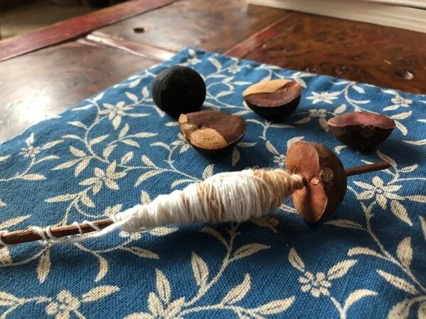 Spindle made from half an avocado pit and a stick. Spinning cotton from a pill bottle.