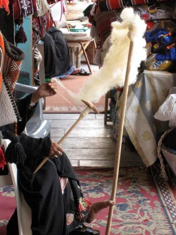 A woman spinning wool in Doha, Qatar (2011) uses her toes to hold a large distaff, freeing both hands to spin.