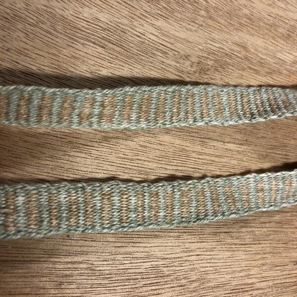 Handwoven natural colored cotton tape, detail, horizontal stripe pattern of brown and green/gray. I like it that the beat is uneven so the lines aren’t really straight. it’s a little wonky, such is life.