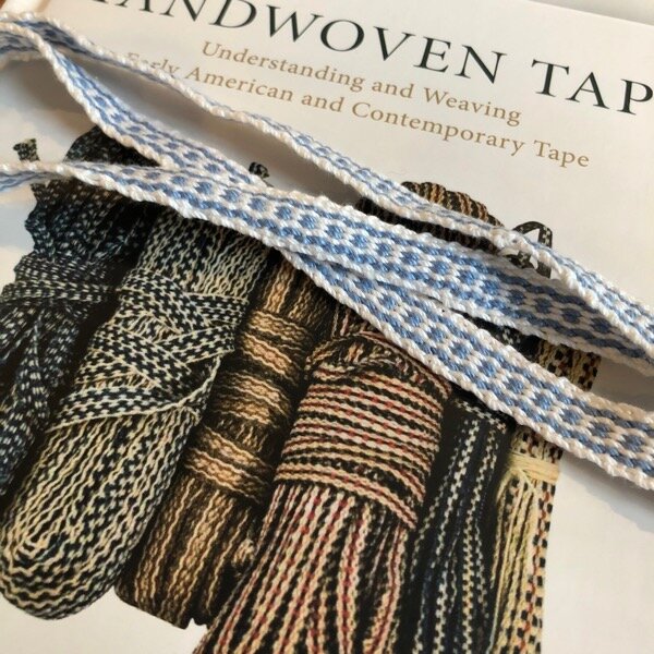 Cover image of Susan Faulkner Weaver book Handwoven Tape, with my crochet cotton blue and white band on top. I was imitating the pattern third from left in the bundles shown.
