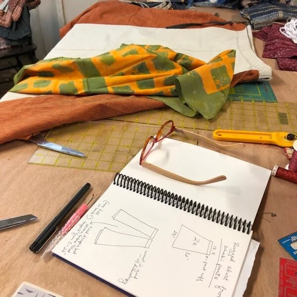 Plotting and scheming - my sewing notebook has the idea and measurements, fabric is being auditioned for pockets. I added the orange fabric by sewing one side to the khaki, then putting it on my body and drawing a line where the other seam needed to be to give me enough flare. Not very scientific.