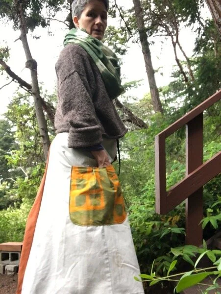 Side view of garden skirt, showing full inverted trouser leg panel, with large yellow &amp; green pocket, discharge dyed with square grid stencil.