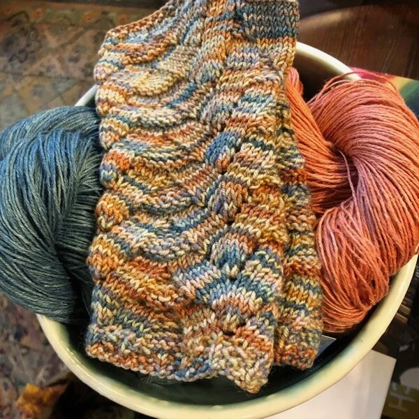 Knitted mitts in variegated wool, on a bowl of hemp yarn dyed with indigo and madder at The Artful Ewe in Port Gamble, WA. My mitts, and yarn that was mine as soon as I paid for it.