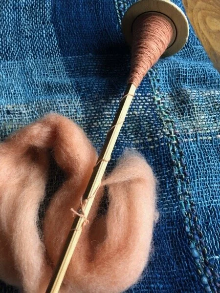 Madder-dyed wool spinning in progress, on a Peruvian spindle. I dyed the fiber in a workshop with Local Color Fiber Studio of Bainbridge Island. The weaving underneath I made with my rigid heddle loom, two shades of indigo cotton from Laos.