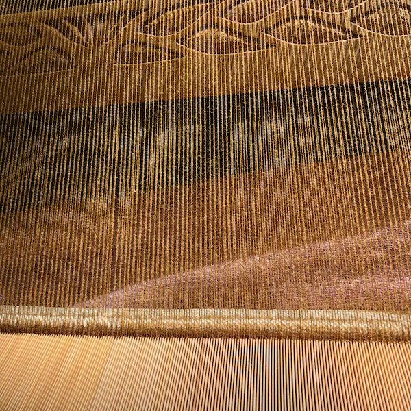 Sunlight on a warp of gold cotton with my bamboo reed and a sword beater carved by Allen Berry.