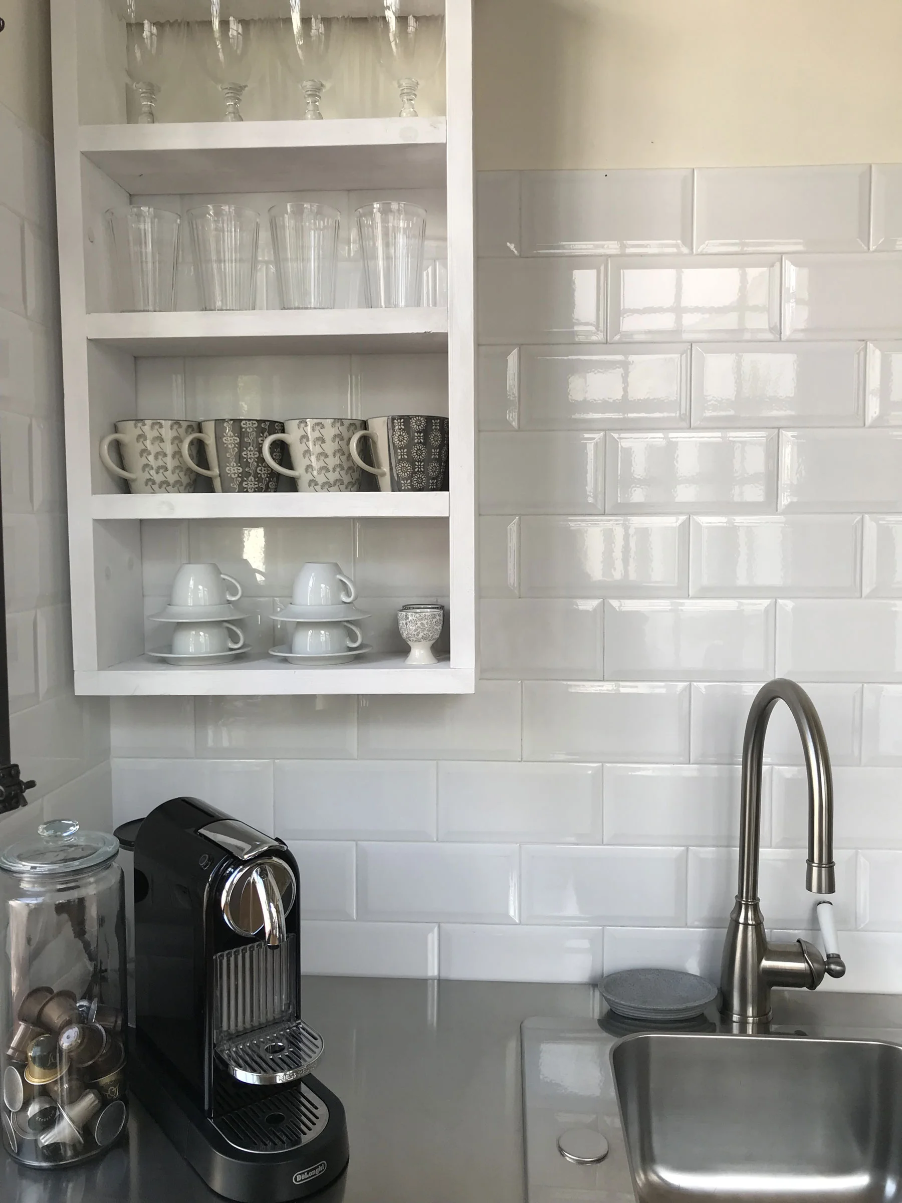 a beautiful kitchen sink with stainless steel counter and white subway tile on the walls