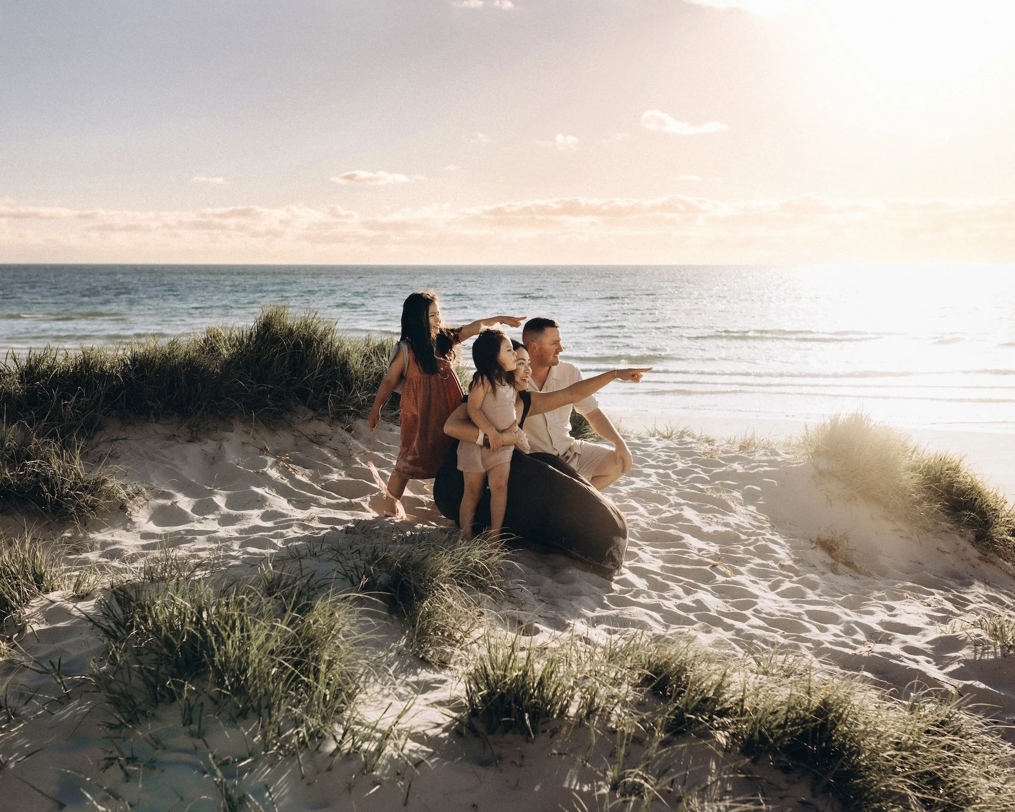 A family enjoying playful, natural moments together on a beautiful mornington peninsula beach during sunset