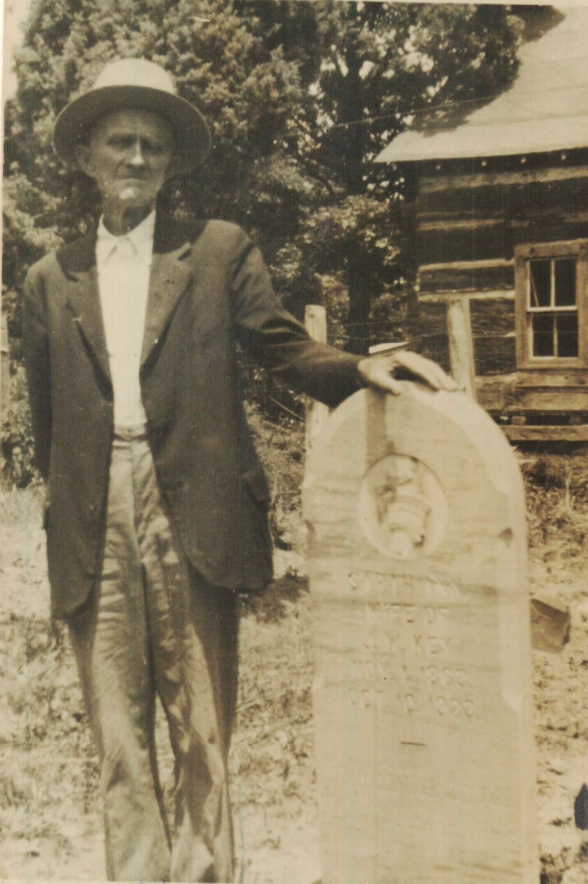 John W. Key poses with his wife's tombstone. Upon john's death, his children erected a new, double stone. However, his youngest son was unable to part with the original stone and it now resides at his home place. I wonder if someone will find it there in years to come and think the grave is there too?